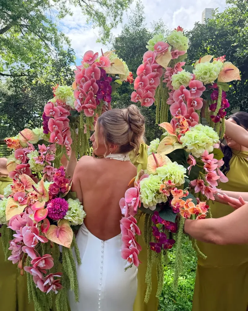 Nevěsta obklopená růžovými orchidejemi, hortenziemi a pestrými svatebními květinami